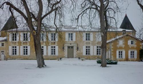 a large yellow building with trees in the snow at Le Logis du Péré in Saint-Coutant-le-Grand