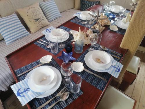 een houten tafel met borden en glazen erop bij Corabia Santa Marina in Sulina