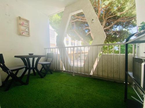 d'un balcon avec une table, des chaises et un arbre. dans l'établissement Studio Cosy - 50m PLAGE - Terrasse - centre ville, à La Grande Motte