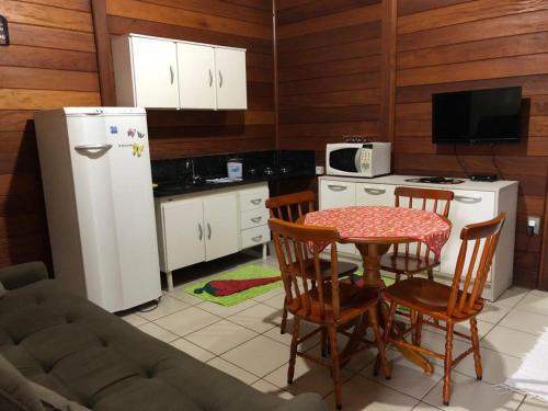 eine Küche mit Tisch und Stühlen und einem Kühlschrank in der Unterkunft Residencial Alvorada in Bombinhas