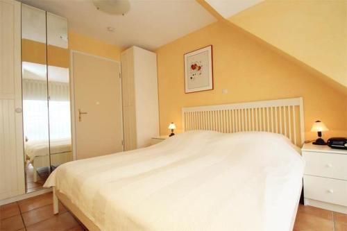 キュールングスボルンにあるStrandstrasse-32-Wohnung-53-129の黄色い壁のベッドルームに白い大型ベッド1台