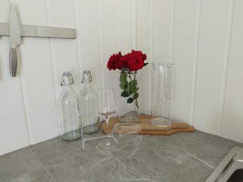 a counter with three glass bottles and a vase with a red rose at Guesthouse with terrace in Arendal