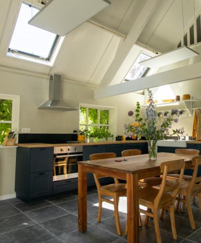a kitchen with a wooden table with chairs and a stove at Het Betuws Erfje in Maurik