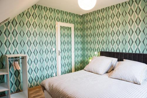 - une chambre avec un lit et un mur vert dans l'établissement Gîte Version 70, à Mondrepuis