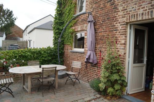 a patio with a table and an umbrella next to a brick building at La Petite Maison in Sart lez Walhain