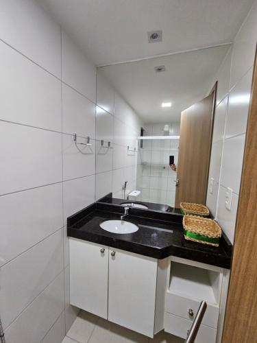 La salle de bains blanche est pourvue d'un lavabo et d'un miroir. dans l'établissement Ap. Novo Maceió - praia de Ponta verde, à Maceió