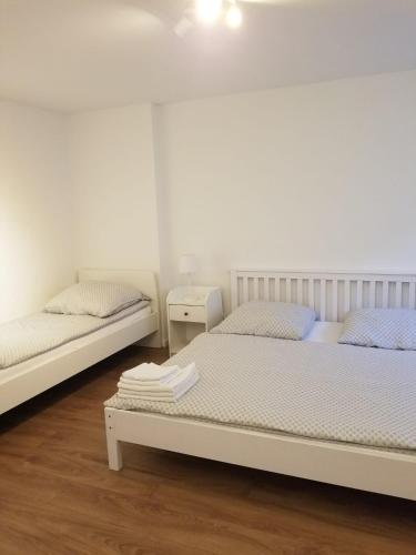 two beds in a bedroom with white walls and wooden floors at Hanse Zeit in Bremen