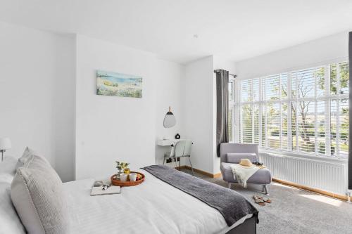 泰格茅斯的住宿－Greenacre - Close to beaches with Hydropool spa，卧室配有床、椅子和窗户。