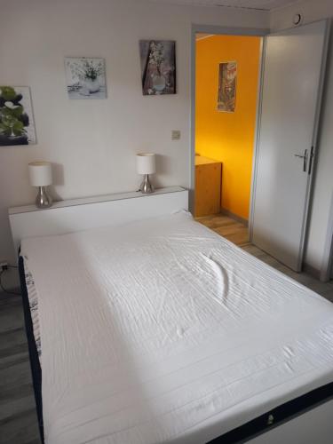 Cette chambre dispose d'un grand lit blanc et d'un mur jaune. dans l'établissement Le Mélusine, à Gérardmer