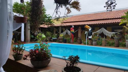 a swimming pool in front of a house with plants at Pousada Cantinho de Casa in Nobres
