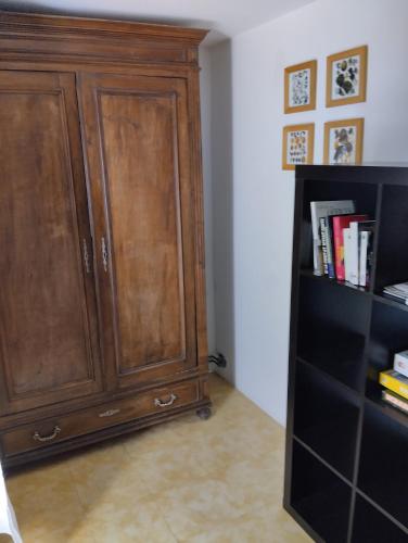 une armoire en bois dans une pièce avec une étagère à livres dans l'établissement Studio calme dans les vignes avec piscine, à Suze-la-Rousse