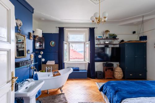 a bathroom with blue walls and a tub and a bed at Victoria Design Stays - Premium Apartment Ohrada in Prague