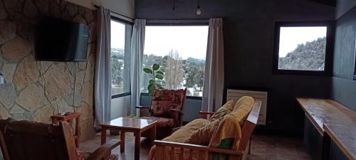 een woonkamer met een bank en 2 ramen bij Los soles de montaña in Villa Pehuenia