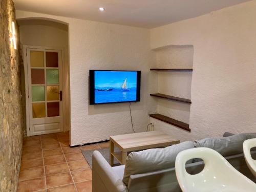 ein Wohnzimmer mit einem Sofa und einem TV an der Wand in der Unterkunft Can Julián in L'Escala