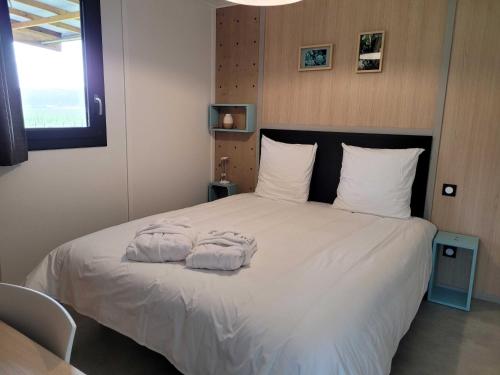 a bedroom with a bed with two towels on it at Les Chalets du Moulin de Valade in Condat-sur-Trincou