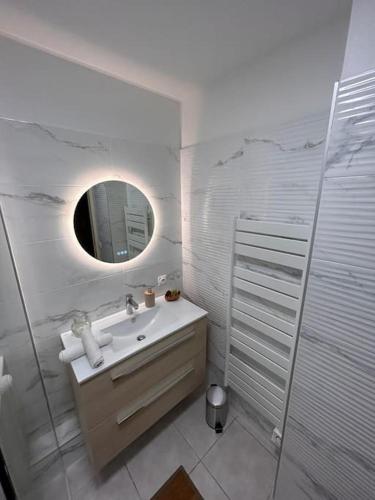 une salle de bain blanche avec un lavabo et un miroir dans l'établissement Nouveau cœur de ville, 100 m de la plage, spacieux, à Sainte-Maxime
