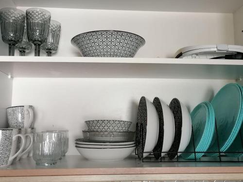 a shelf with plates and bowls and wine glasses at Nest by the Sea in Perea