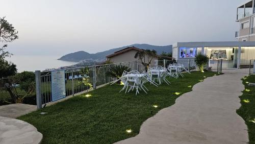 a patio with white tables and chairs on the grass at Miramare Castellabate Resort in Santa Maria di Castellabate