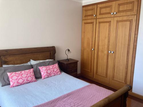 a bedroom with a bed with two pink pillows at Tia Rita House in Figueira da Foz