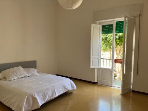 een witte slaapkamer met een bed en een open deur bij STAR HOUSE CASA VACANZE in Marsala