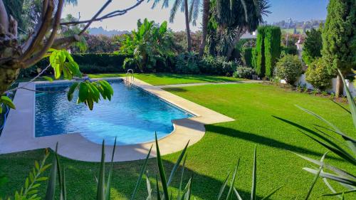 una piscina en un jardín con césped y árboles en Cortijo De Cortes, en Estepona