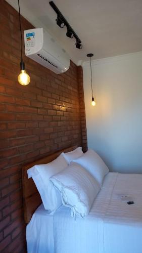 a bedroom with a white bed with a brick wall at Pousada Bem Viver in Nobres