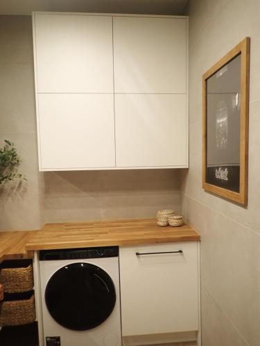 a kitchen with white cabinets and a black and white dishwasher at Apartament Narutowicza 56 in Łódź