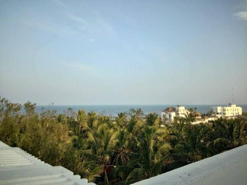 vistas a una playa con palmeras y al océano en Sea View apartment next to Surf Turf - Kovalam, en Covelong