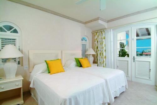 um quarto com uma cama branca com almofadas amarelas e verdes em Sunny Vacation Villa No 13 em Saint James