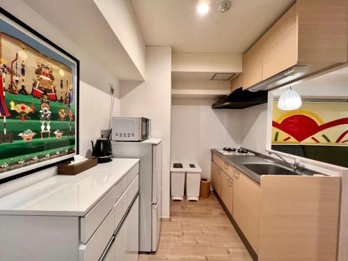 a kitchen with a sink and a large tv on the wall at 浅草寺3分 浅草駅6分 2寝室+リビング2-6人 スカイツリービュー 駅近 成田空港&羽田空港直通 in Tokyo