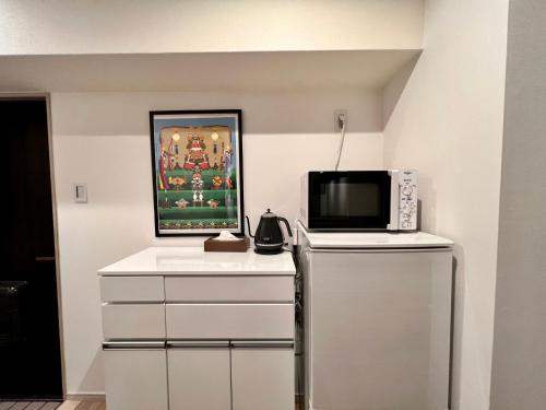 a kitchen with a microwave and a tv on a counter at 浅草寺3分 浅草駅6分 2寝室+リビング2-6人 スカイツリービュー 駅近 成田空港&羽田空港直通 in Tokyo