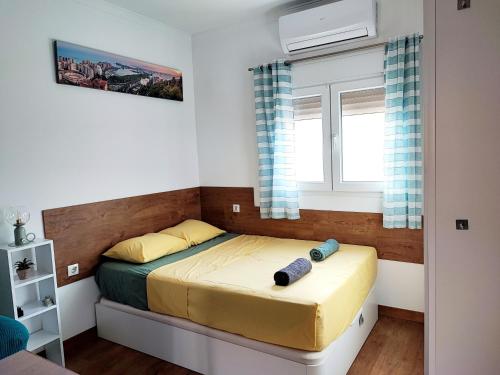 Un dormitorio pequeño con una cama y dos ventanas. en Bright and quiet studio in Málaga, en Málaga