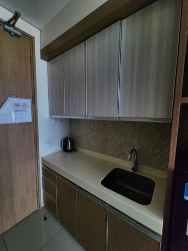 a kitchen with a sink and wooden cabinets at Troom treepark city apartement in Kebun Nanas