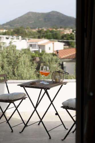 a glass of wine sitting on a table on a balcony at Sunrise Sardinia Posada in Posada