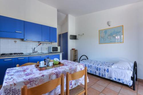 a kitchen with blue cabinets and a table and a bed at Residenza Elbamare in Capoliveri
