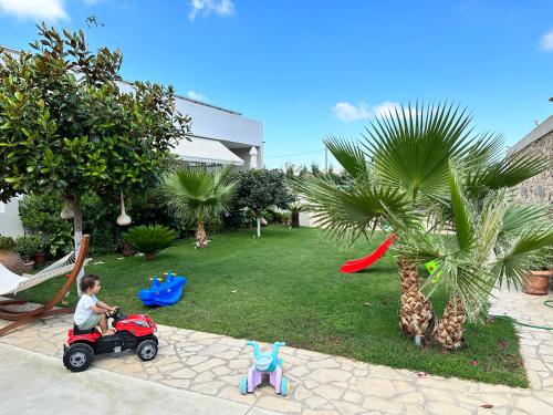 a young boy riding a toy motorcycle in a backyard at BIO Garden Stonehouse in Gonia