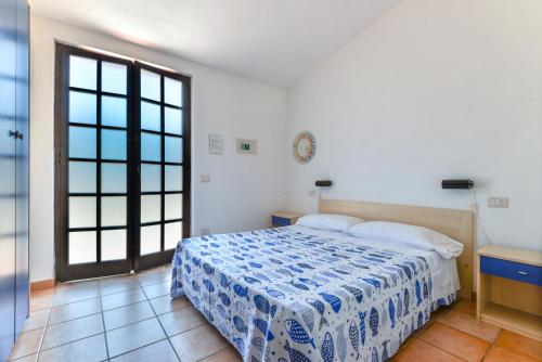 a bedroom with a bed with a blue and white blanket at Residenza Elbamare in Capoliveri
