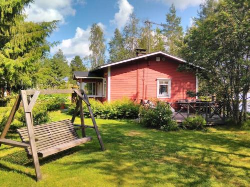 una casa roja con un banco delante en Lysti Cottage by the lake and magical countryside, en Rovaniemi