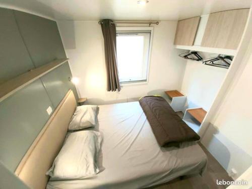 um pequeno quarto com uma cama e uma janela em Mobil home climatisé 6pers. 3CH camping domaine de chaussy 5* Ardèche em Lagorce