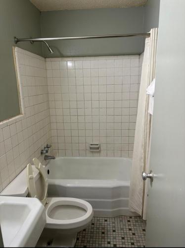 a bathroom with a toilet and a tub and a sink at Travel Inn Montgomery AL in Montgomery