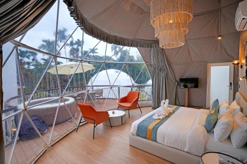 a bedroom with a bed and a tub in a tent at Le Villagio Resort & Domes in Sultan Bathery