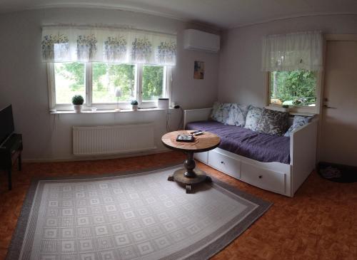 a bedroom with a bed and a table and windows at Stuga vad vatten in Åsarp
