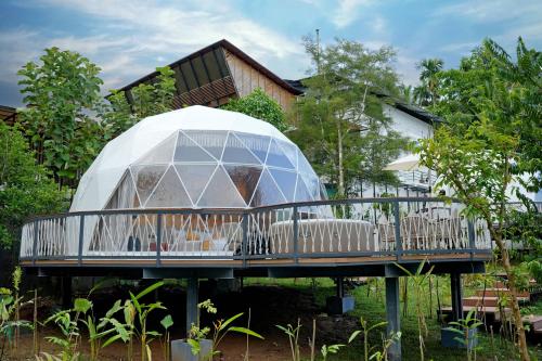 a glass dome on a deck in front of a house at Le Villagio Resort & Domes in Sultan Bathery