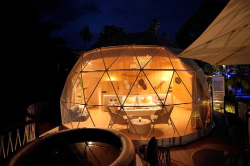 a large glass dome with a room in it at night at Le Villagio Resort & Domes in Sultan Bathery