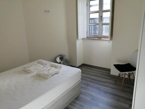 ein weißes Schlafzimmer mit einem Bett und einem Fenster in der Unterkunft Cantinho da Karine in Maia