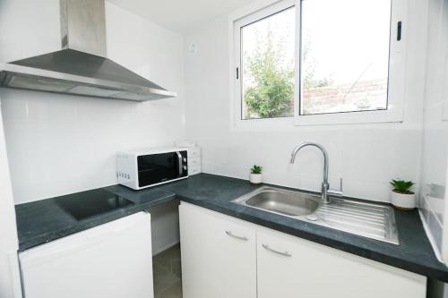 a white kitchen with a sink and a microwave at Le Coquet-T1 21m2-Proche Paris Metro 7 in Aubervilliers