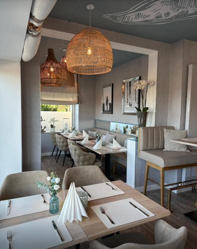 a dining room with tables and chairs and a chandelier at Seaside-Strandhotel in Timmendorfer Strand