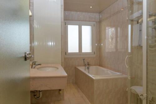 een badkamer met een wastafel, een bad en een raam bij Hôtel de la cloche in Vitry-le-François