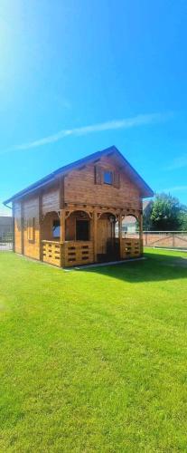 uma cabana de madeira num campo de relva verde em Ostoja Struga em Świnoujście