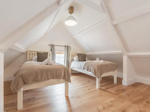 a attic bedroom with two beds and a mirror at The Red Rooster - Uk44440 in Arlingham